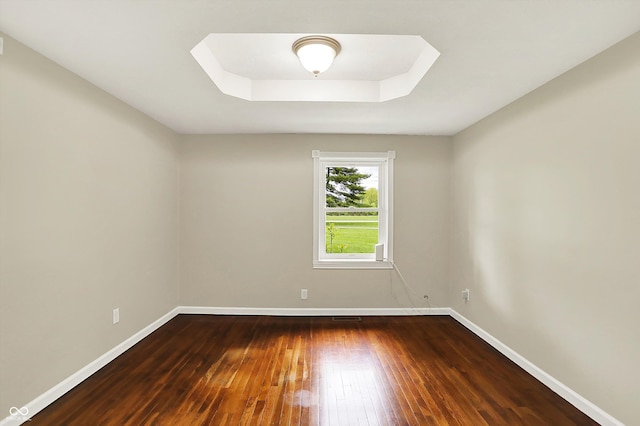 unfurnished room featuring hardwood / wood-style flooring, baseboards, and a raised ceiling