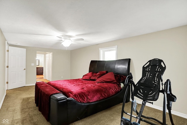 carpeted bedroom with baseboards, ensuite bath, and a ceiling fan