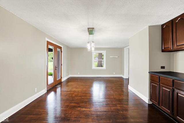 unfurnished dining area featuring dark wood-type flooring, baseboards, a textured ceiling, and french doors