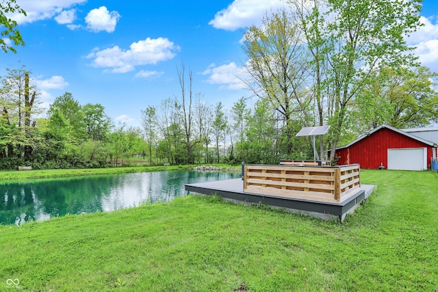 view of green lawn featuring a detached garage, a deck with water view, and an outdoor structure