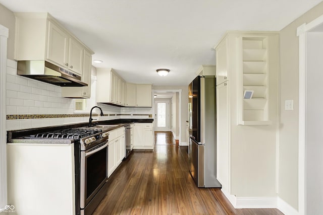 kitchen featuring stainless steel appliances, under cabinet range hood, dark wood-style flooring, baseboards, and a sink