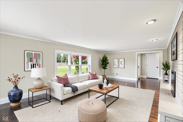 living room featuring dark wood-style floors, baseboards, ornamental molding, and a fireplace with flush hearth