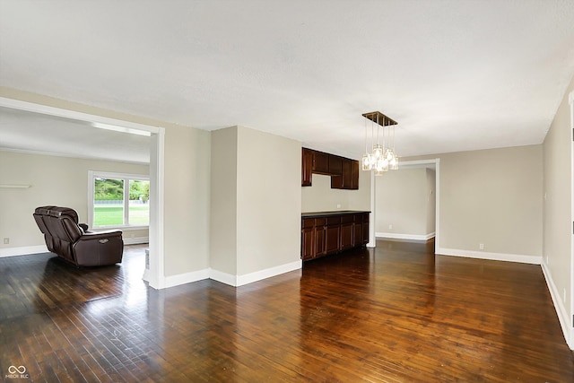 unfurnished living room featuring a chandelier, dark wood-style floors, and baseboards