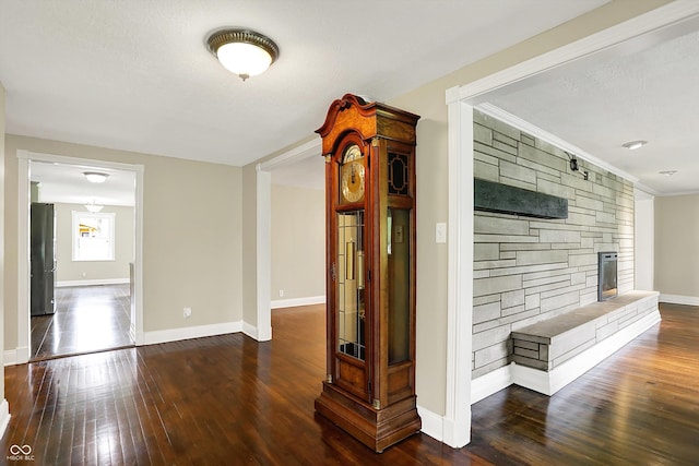 hall featuring hardwood / wood-style floors, baseboards, crown molding, and a textured ceiling