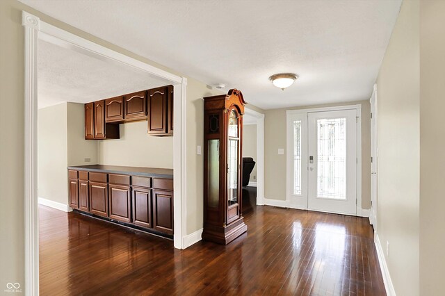 foyer entrance featuring dark wood-style floors and baseboards