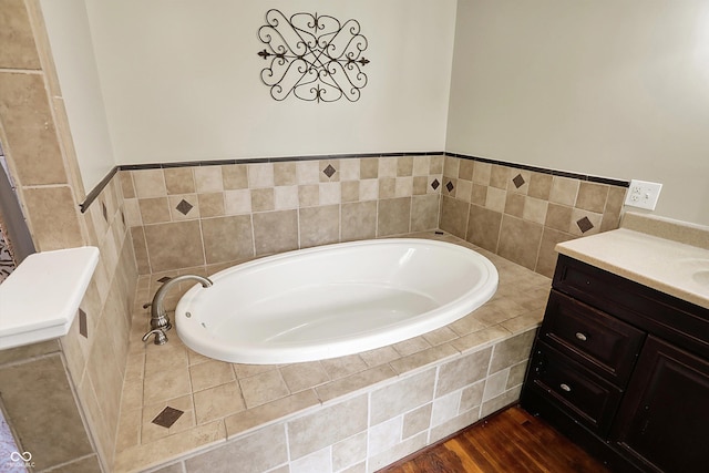 full bathroom featuring a garden tub, vanity, and wood finished floors
