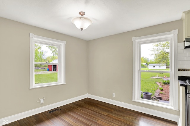empty room featuring baseboards, plenty of natural light, and dark wood finished floors