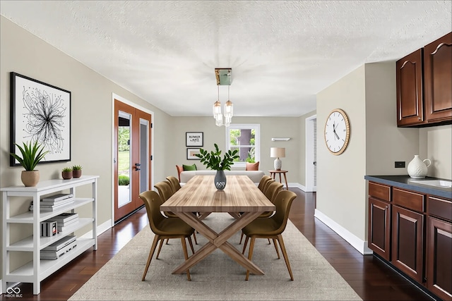 dining area with dark wood-style flooring, a textured ceiling, and baseboards