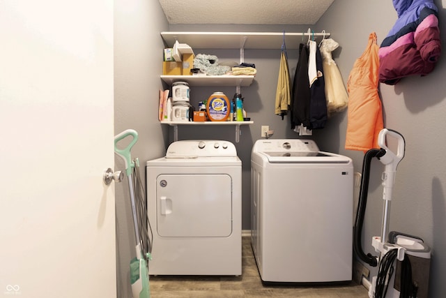 laundry area featuring laundry area, a textured ceiling, light wood-type flooring, and washer and dryer