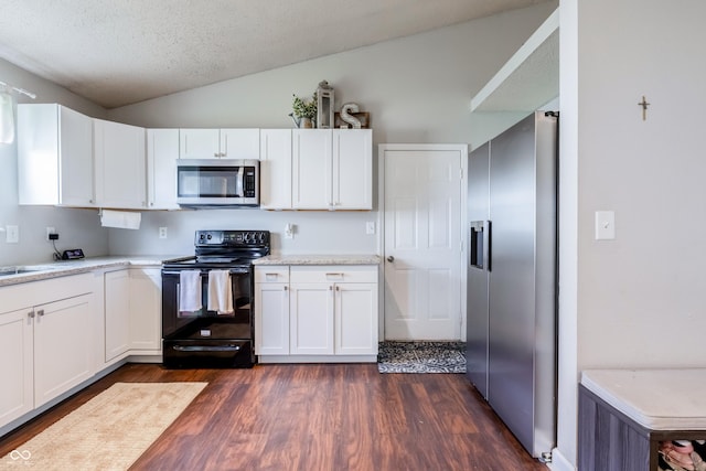 kitchen with lofted ceiling, dark wood finished floors, white cabinets, and appliances with stainless steel finishes