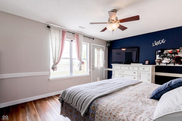 bedroom featuring hardwood / wood-style flooring, baseboards, a ceiling fan, and visible vents