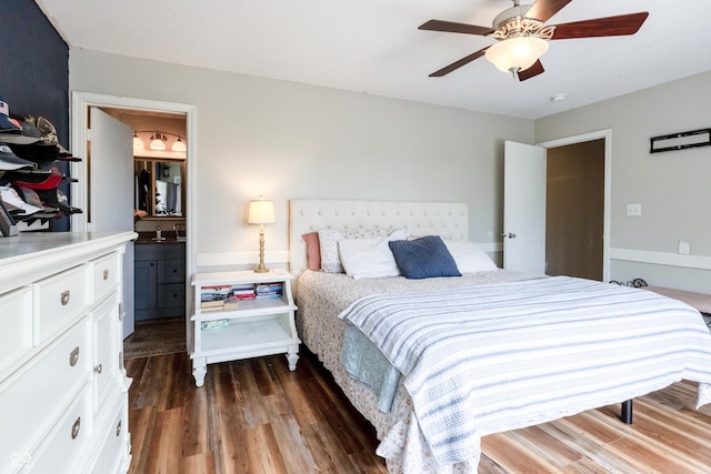 bedroom featuring a ceiling fan, ensuite bath, and dark wood-style floors