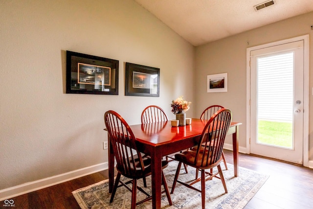dining area with baseboards, vaulted ceiling, visible vents, and wood finished floors