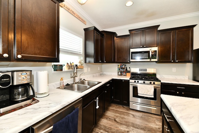 kitchen featuring dark brown cabinets, appliances with stainless steel finishes, a sink, light wood-type flooring, and ornamental molding