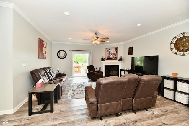 living room with crown molding, light wood finished floors, and ceiling fan