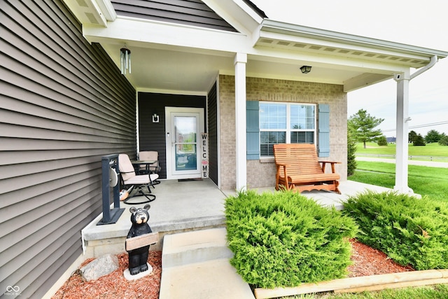 entrance to property featuring covered porch and brick siding