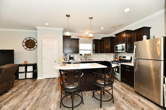 kitchen with light countertops, appliances with stainless steel finishes, a kitchen island, and light wood-style flooring