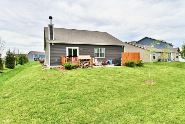 back of house featuring a lawn, fence, a chimney, and a deck