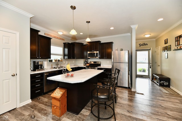 kitchen featuring dark wood-style flooring, appliances with stainless steel finishes, a center island, light countertops, and a sink