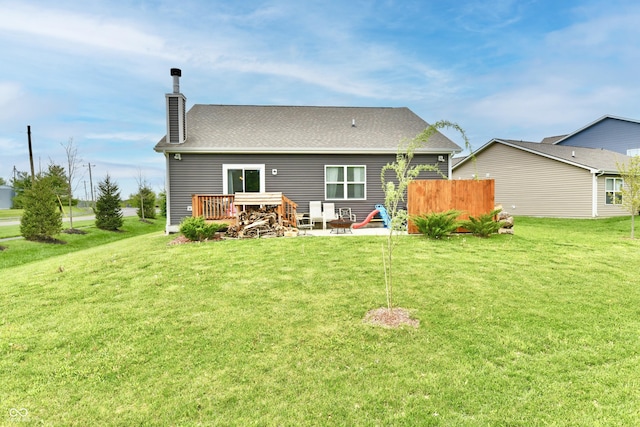 rear view of house with a lawn, fence, a chimney, and a deck