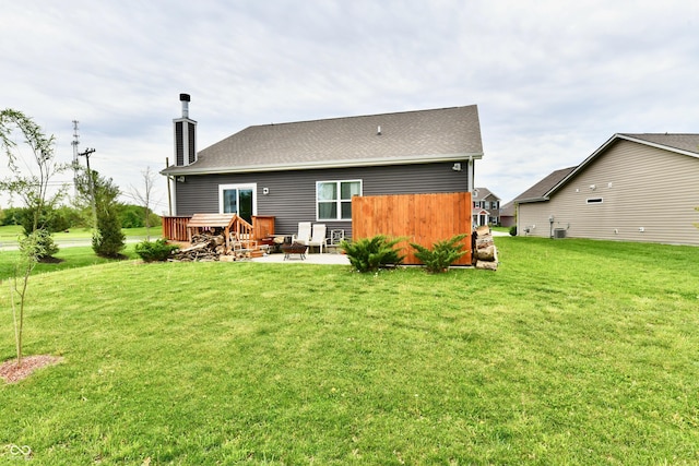 rear view of house featuring a lawn, a chimney, and a patio area