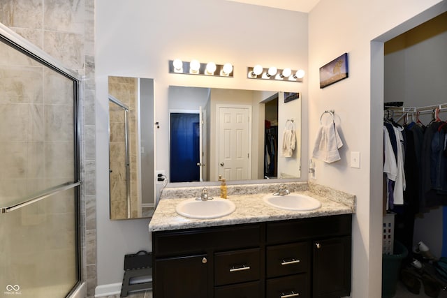 full bathroom featuring a sink, a tile shower, double vanity, and a spacious closet