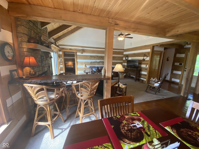 dining space with a bar, a ceiling fan, vaulted ceiling with beams, and wooden ceiling