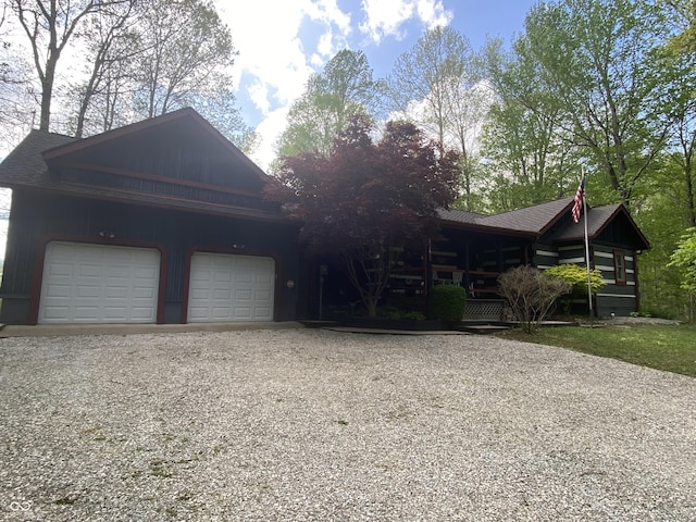 view of front facade with a porch, driveway, a shingled roof, and a garage
