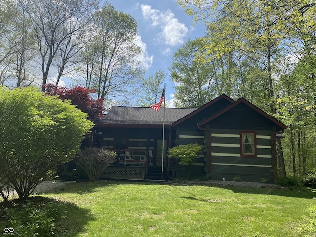 view of front of house with a porch, a front lawn, and log exterior