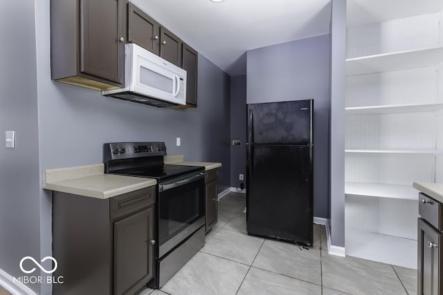 kitchen with electric range, light tile patterned flooring, light countertops, freestanding refrigerator, and white microwave