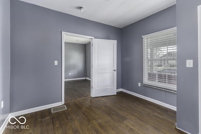 empty room featuring baseboards, wood finished floors, and visible vents