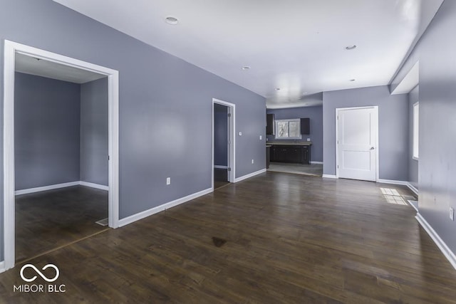 unfurnished living room featuring baseboards and dark wood-type flooring