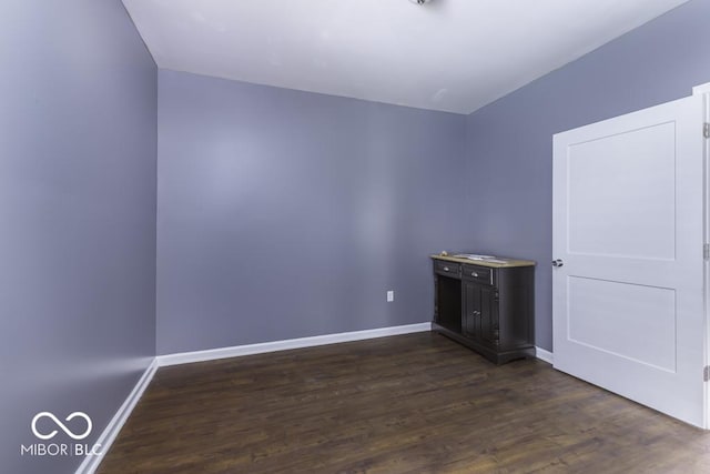 empty room featuring baseboards and dark wood-style floors