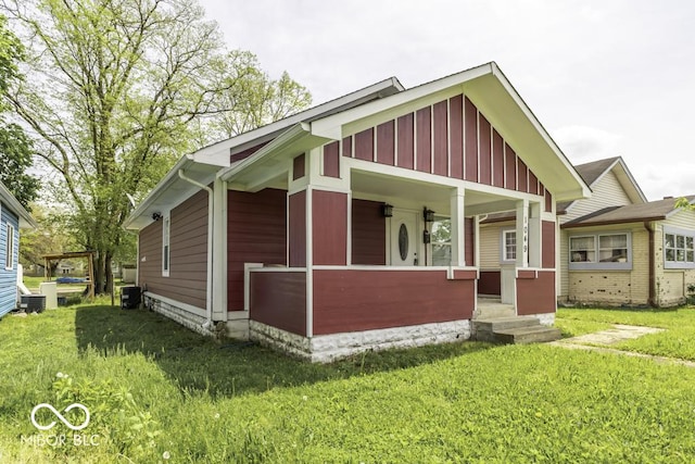 exterior space with board and batten siding, cooling unit, and a front yard