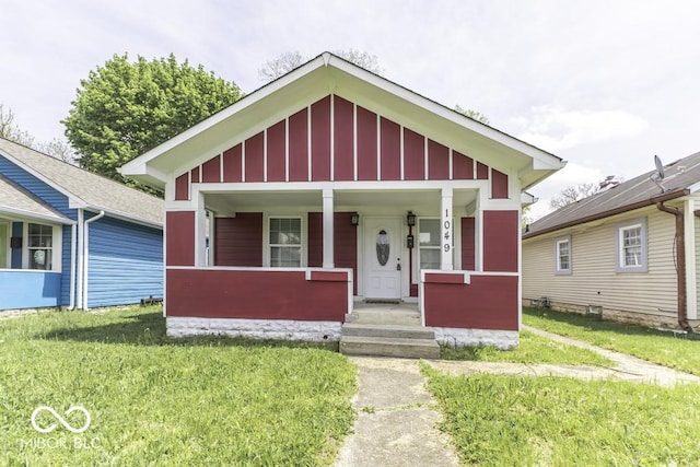 view of front facade with board and batten siding, covered porch, and a front yard