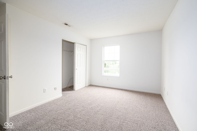 unfurnished bedroom with baseboards, carpet, a closet, and visible vents