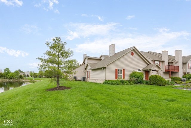 view of side of home with a lawn, central air condition unit, a water view, and a chimney