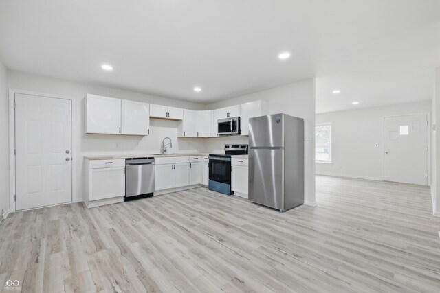 1116 Heatherwood Dr, Indianapolis, IN 46241 - kitchen with appliances with stainless steel finishes, a sink, light countertops, white cabinets, and light wood-style flooring