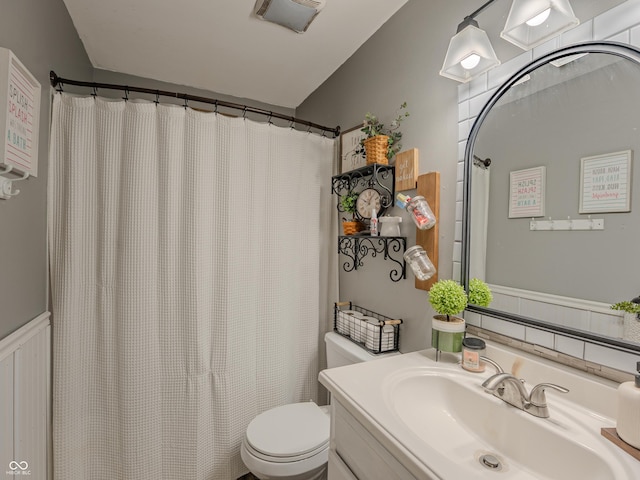 632 Woodside Ct, Seymour, IN 47274 - bathroom with visible vents, vaulted ceiling, wainscoting, vanity, and toilet