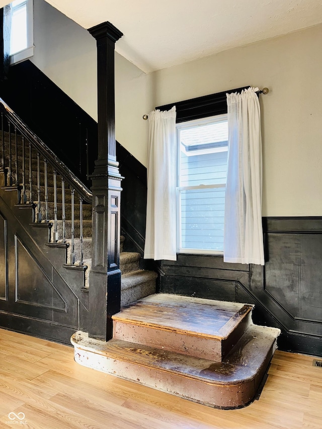 staircase with ornate columns and wood finished floors