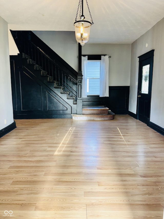 interior space with stairway, baseboards, an inviting chandelier, and light wood finished floors