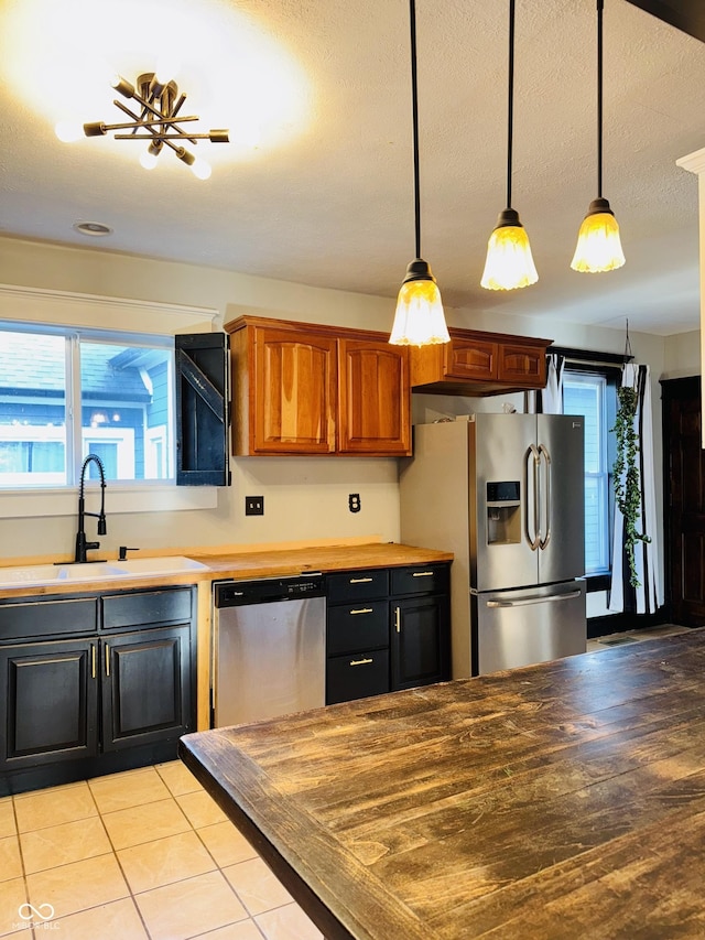 kitchen featuring stainless steel appliances, decorative light fixtures, plenty of natural light, and a sink