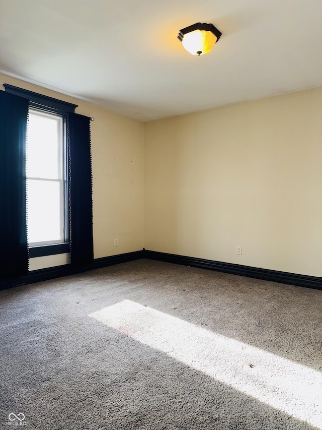 carpeted empty room featuring baseboards