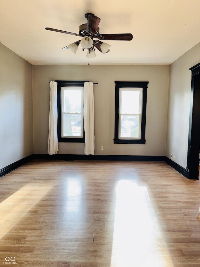 unfurnished room with a ceiling fan, baseboards, and light wood-style flooring