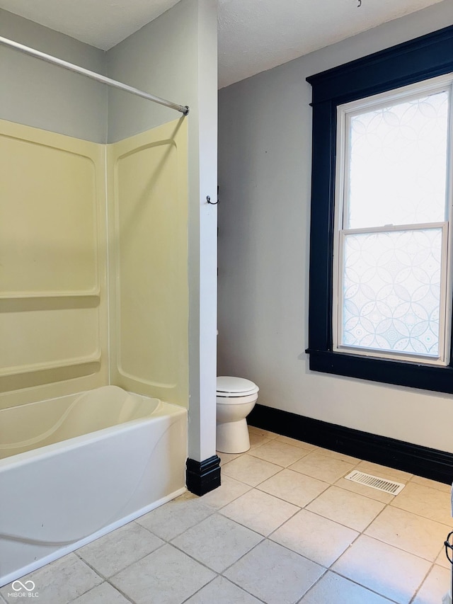 bathroom featuring toilet, tile patterned floors, baseboards, tub / shower combination, and visible vents