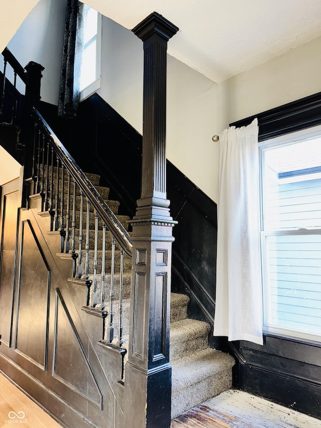 staircase with decorative columns and wood finished floors