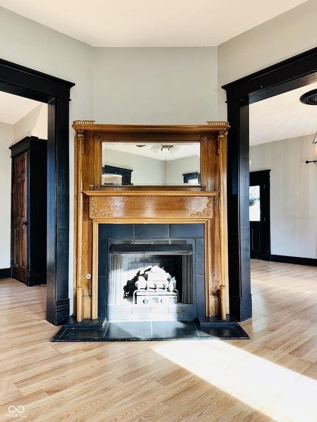 details featuring a fireplace with flush hearth, baseboards, and wood finished floors