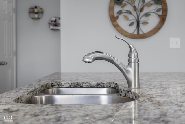 room details with light stone countertops and a sink