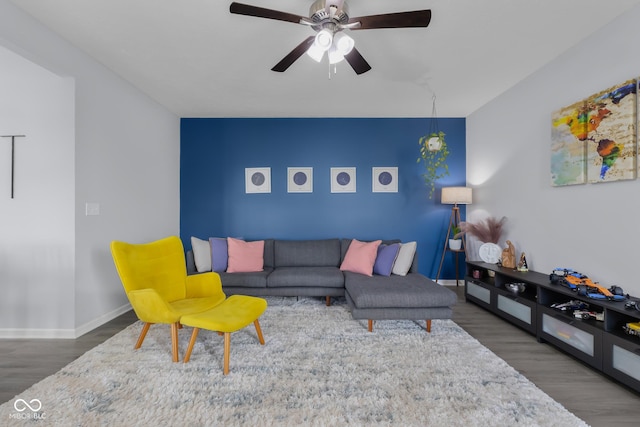 living area with baseboards, a ceiling fan, and wood finished floors