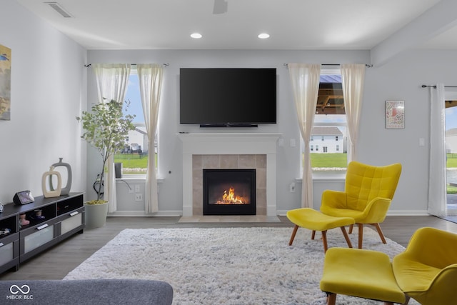 living area featuring a tiled fireplace, recessed lighting, baseboards, wood finished floors, and visible vents